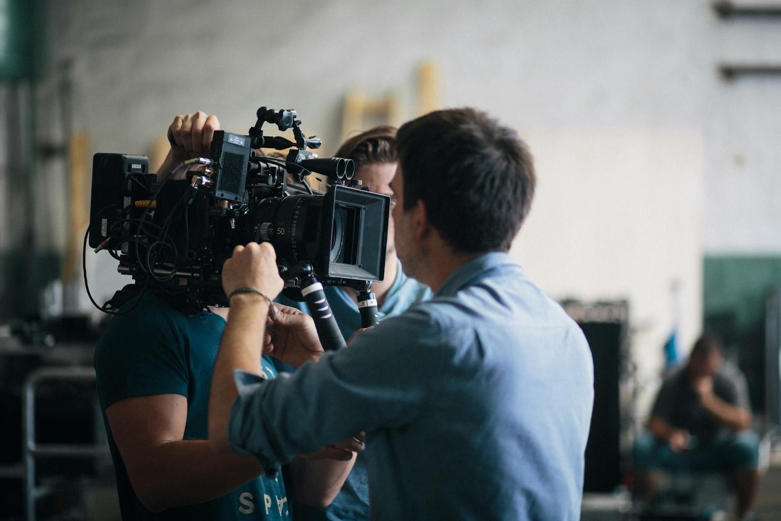 A film crew adjusting a video camera on an indoor set, focusing on technical preparation and teamwork.