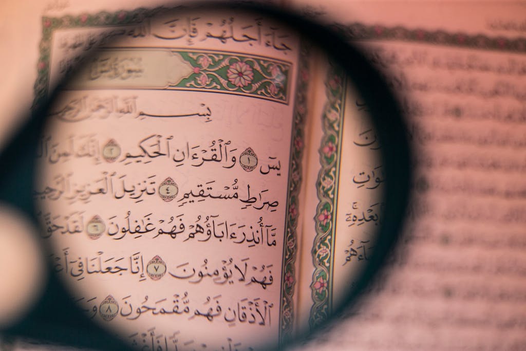 Close-up of Arabic script in the Quran viewed through a magnifying glass, symbolizing faith and study.
